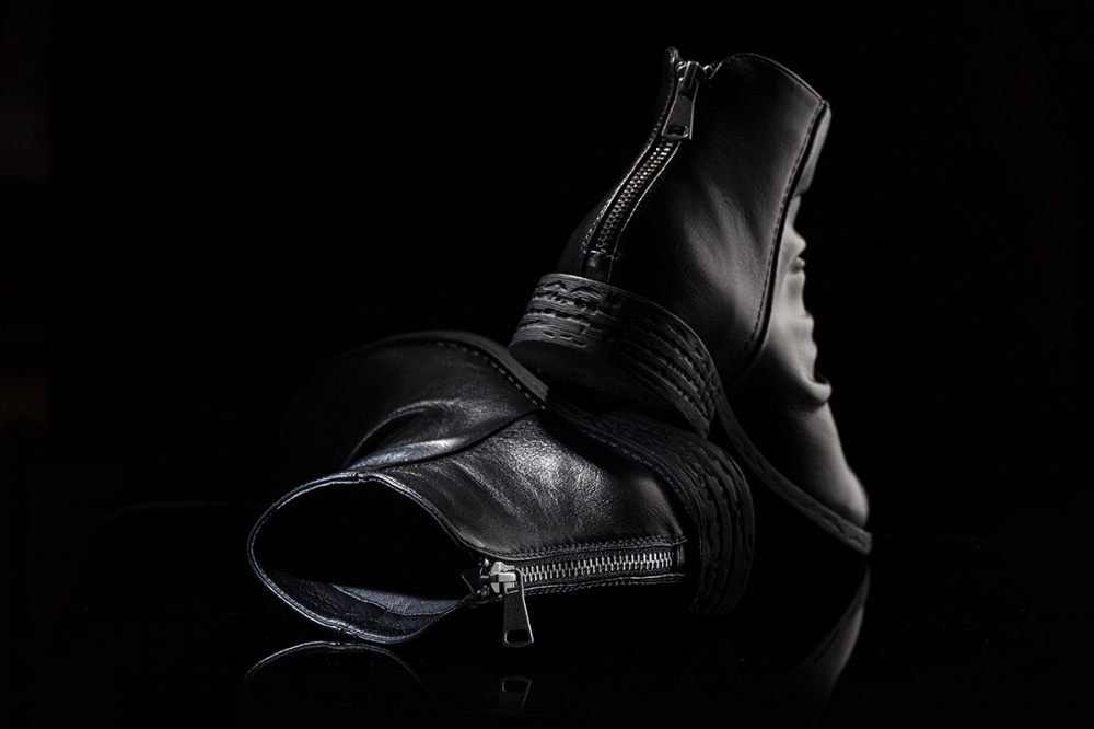 Fotografia prodotto di scarpa nera in composizione still life su sfondo scuro