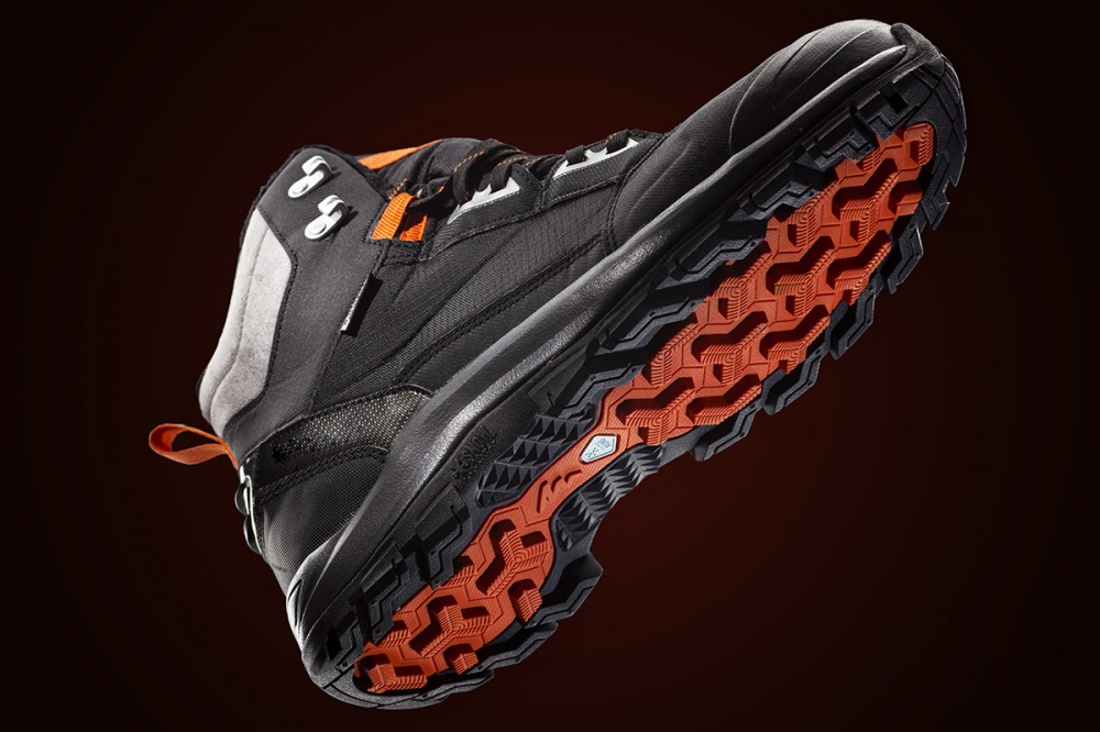 Fotografia prodotto di scarpa tecnica con suola arancione su sfondo scuro